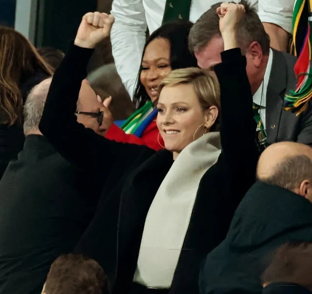 Princess Charlene wore a black wool coat by Akris. Gold hoop earrings. South Africa national rugby union team Springboks