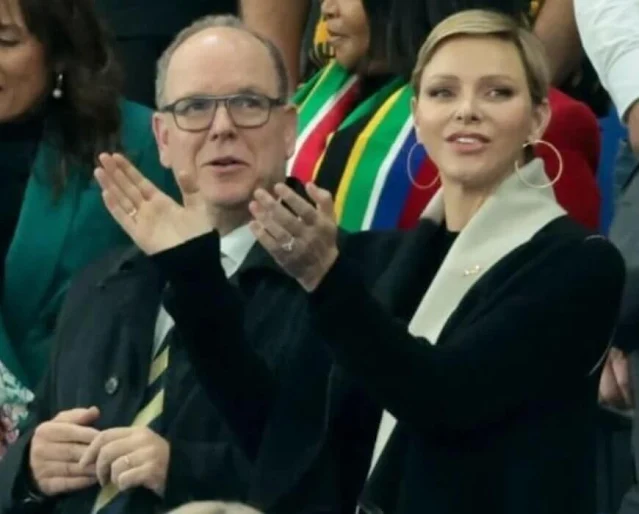 Princess Charlene wore a black wool coat by Akris. Gold hoop earrings. South Africa national rugby union team Springboks