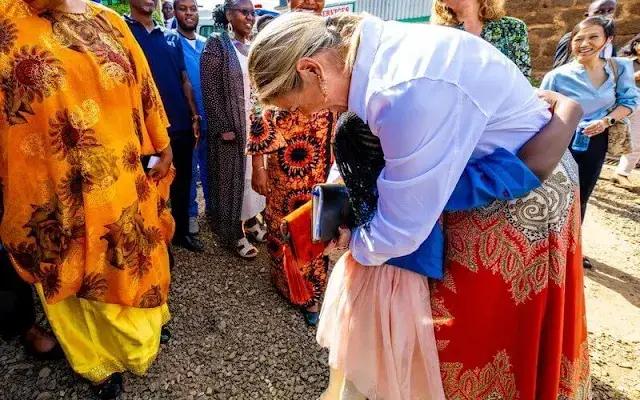 Queen Maxima wore a multicolor paisley print skirt by Etro. White silk shirt. Orange coral earrings and red leather pumps and clutch