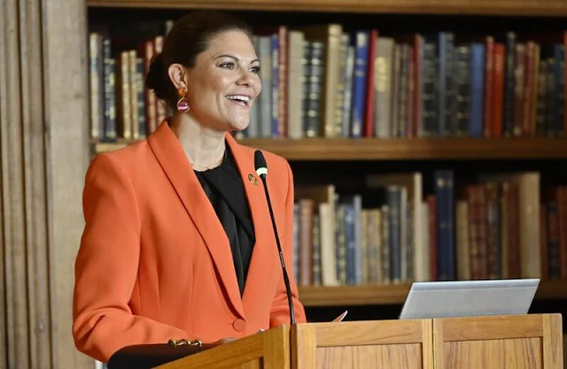 Crown Princess Victoria wore an orange shawl lapel blazer by Zara. By Malina black silk blouse. Black trousers