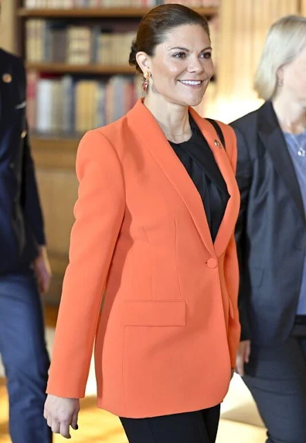 Crown Princess Victoria wore an orange shawl lapel blazer by Zara. By Malina black silk blouse. Black trousers