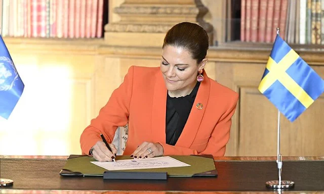 Crown Princess Victoria wore an orange shawl lapel blazer by Zara. By Malina black silk blouse. Black trousers