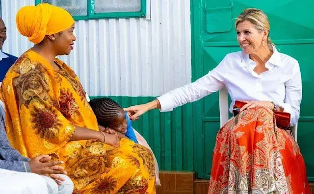 Queen Maxima wore a multicolor paisley print skirt by Etro. White silk shirt. Orange coral earrings and red leather pumps and clutch